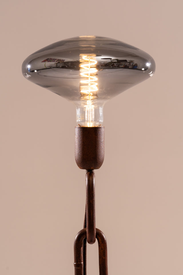 Dettaglio ravvicinato della lampadina LED fumé su supporto artigianale in catena marina, con cavo nascosto tra le maglie