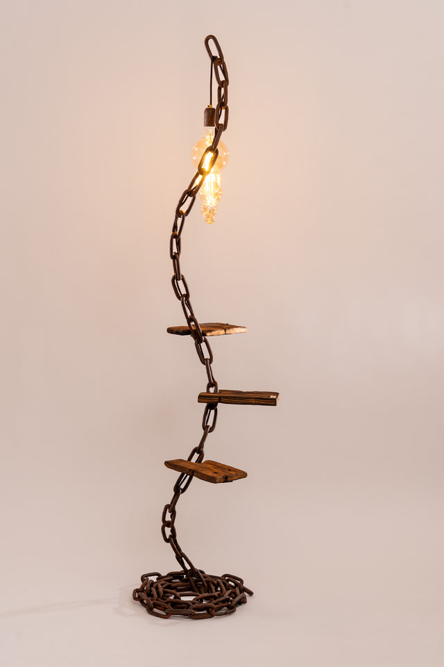 Lampada Scilla con struttura in catena arrugginita modellata a spirale verticale e tre ripiani in legno naturale. Luce decorativa sospesa