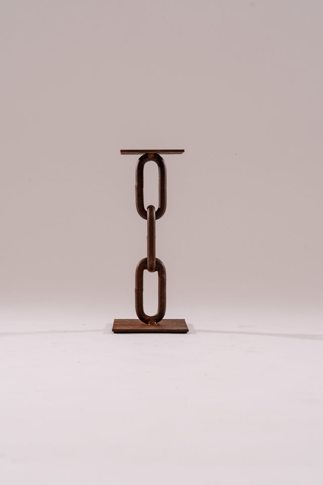 Portacandele Bitta in catena navale con due maglie saldate e base quadrata in metallo ossidato, dal design scultoreo e minimale